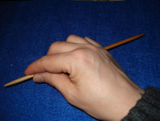 … die Stricknadel in die rechte Hand nehmen (beim Linkshänder vermutlich umgekehrt), so dass die Spitze zwischen Daumen und Zeigefinger genommen werden kann...